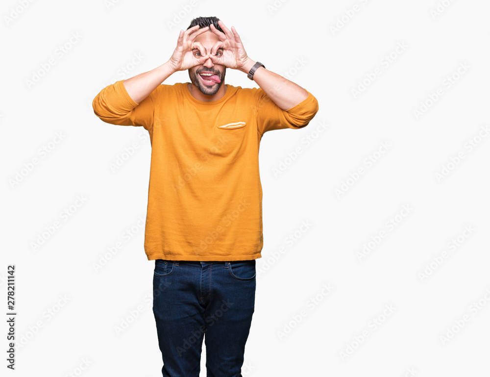 Young handsome man over isolated background doing ok gesture like binoculars sticking tongue out, eyes looking through fingers. Crazy expression. Young handsome man over isolated background doing ok gesture like binoculars sticking tongue out, eyes looking through fingers. Crazy expression.
