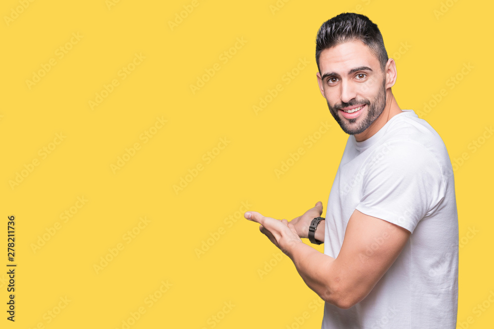 Handsome man wearing white t-shirt over yellow isolated background Inviting to enter smiling natural with open hand Handsome man wearing white t-shirt over yellow isolated background Inviting to enter smiling natural with open hand
