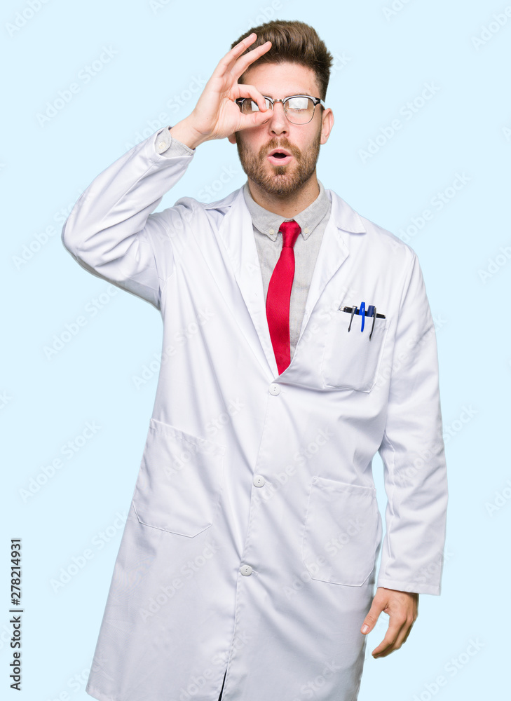 Young handsome scientist man wearing glasses doing ok gesture shocked with surprised face, eye looking through fingers. Unbelieving expression. Young handsome scientist man wearing glasses doing ok gesture shocked with surprised face, eye looking through fingers. Unbelieving expression.