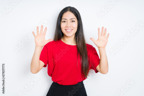 Beautiful brunette woman wearing red t-shirt over isolated background showing and pointing up with fingers number ten while smiling confident and happy. © Krakenimages.com