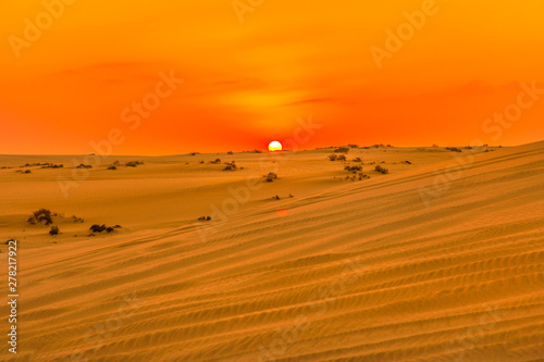 Red and orange colors of sunset sky over sand dunes at Inland Sea. Desert landscape near Qatar and Saudi Arabia. Khor Al Udeid, Persian Gulf, Middle East. Discovery and adventure travel concept.