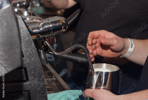 Close-up of hands of barista heating milk in a coffee machine for a client. Man makes coffee in the coffee machine.
