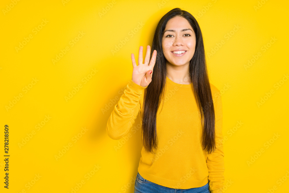 Beautiful brunette woman over yellow isolated background showing and pointing up with fingers number four while smiling confident and happy. Beautiful brunette woman over yellow isolated background showing and pointing up with fingers number four while smiling confident and happy.