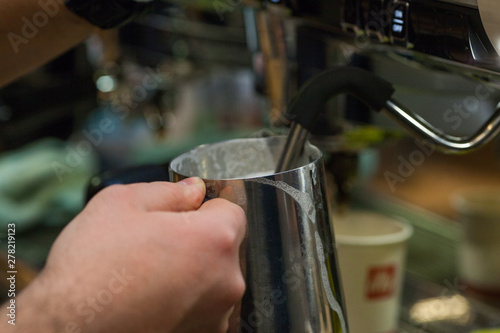 Close-up of hands of barista heating milk in a coffee machine for a client. Man makes coffee in the coffee machine.