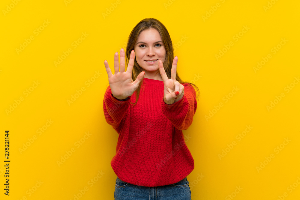 Young woman over yellow wall counting seven with fingers Young woman over yellow wall counting seven with fingers