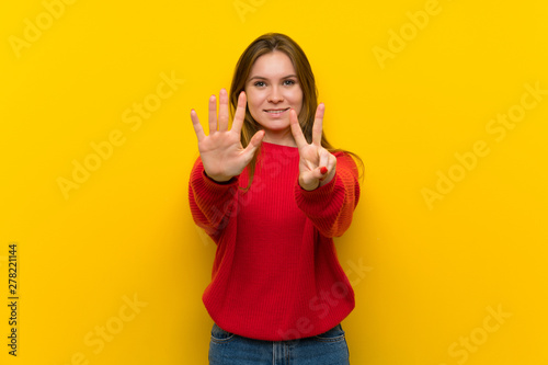 Young woman over yellow wall counting seven with fingers © luismolinero