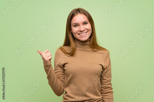 Young woman with turtleneck sweater pointing to the side to present a product