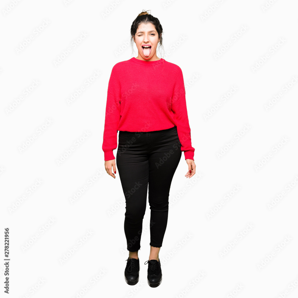 Young beautiful woman wearing red sweater and bun sticking tongue out happy with funny expression. Emotion concept. Young beautiful woman wearing red sweater and bun sticking tongue out happy with funny expression. Emotion concept.