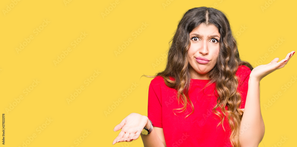 Young beautiful woman wearing casual t-shirt clueless and confused expression with arms and hands raised. Doubt concept. Young beautiful woman wearing casual t-shirt clueless and confused expression with arms and hands raised. Doubt concept.