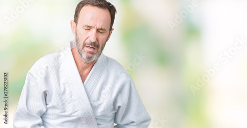 Handsome middle age senior man wearing kimono uniform over isolated background with hand on stomach because indigestion, painful illness feeling unwell. Ache concept.