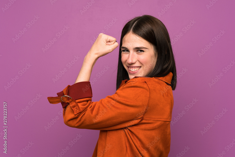 Young woman with a coat over isolated purple background making strong gesture Young woman with a coat over isolated purple background making strong gesture