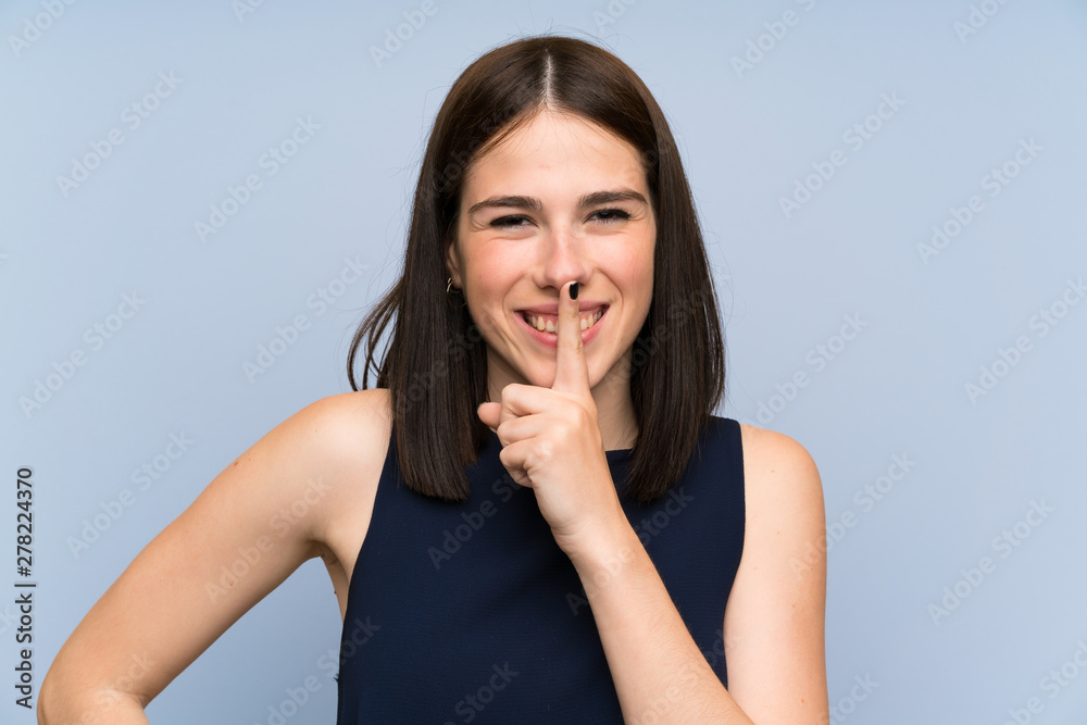 Young woman over isolated blue wall doing silence gesture Young woman over isolated blue wall doing silence gesture
