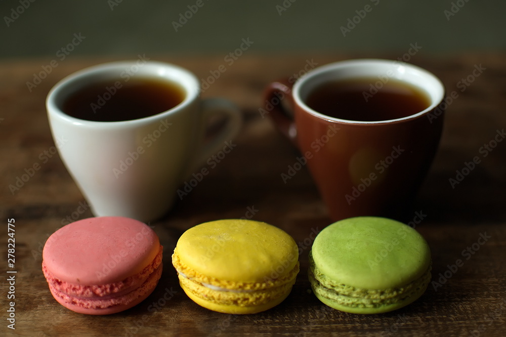 Multi-colored macaroons on a wooden tray. Pink, yellow and green macaroon. Multi-colored macaroons on a wooden tray. Pink, yellow and green macaroon.