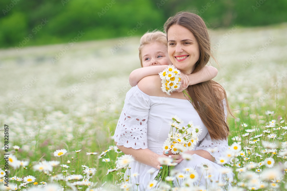 Happy mother and daughter in camomile meadow.