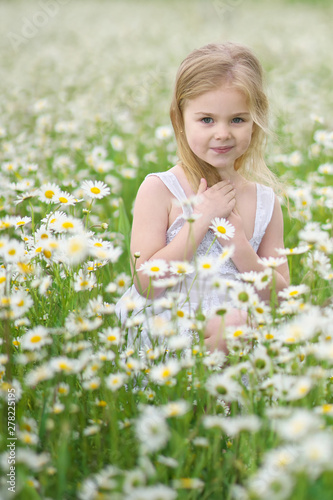Cute little girl in big camomile meadow