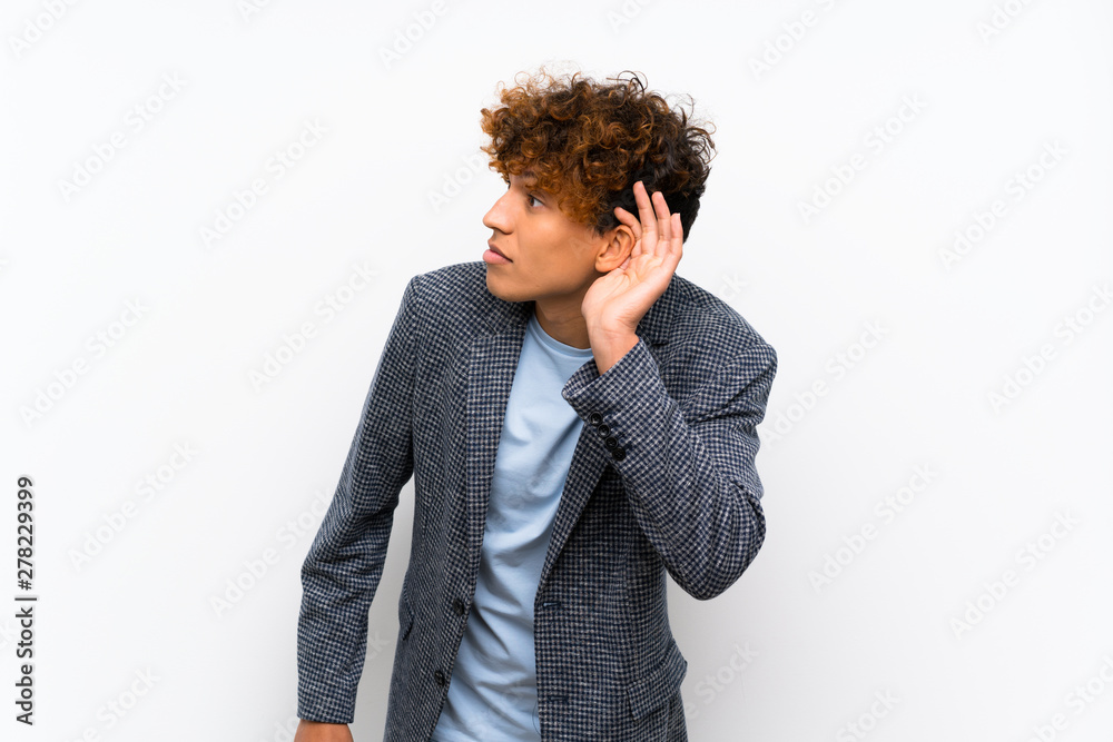 Fashion african american man over isolated white wall listening to something by putting hand on the ear Fashion african american man over isolated white wall listening to something by putting hand on the ear