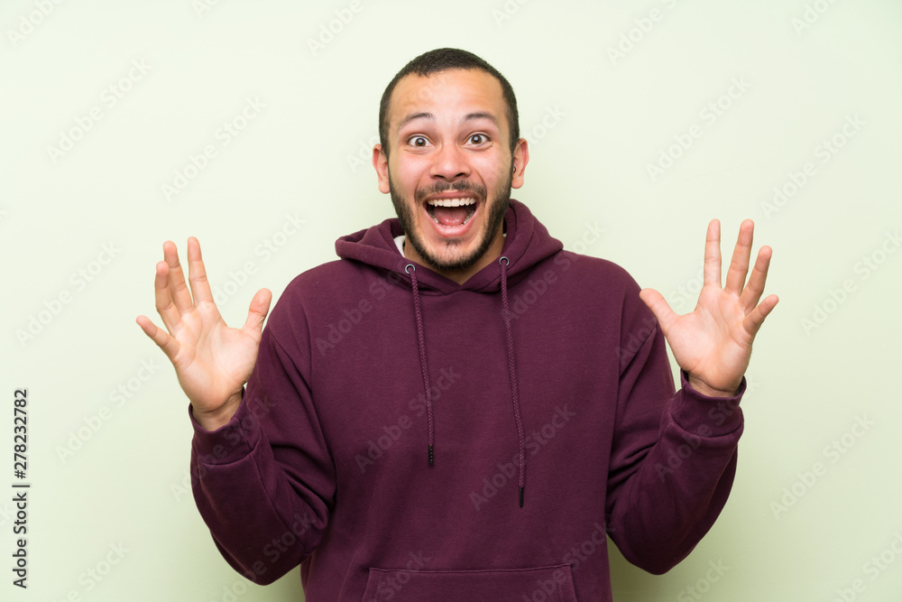Fototapeta premium Colombian man with sweatshirt over green wall with surprise facial expression