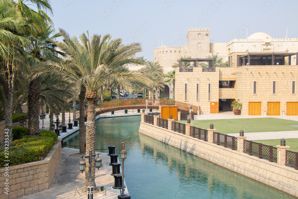 Fototapeta Palm tree with Arabic buildings in Dubai, United Arab Emirates