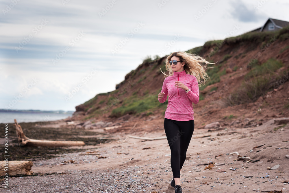 Blonde woman running by the coastline