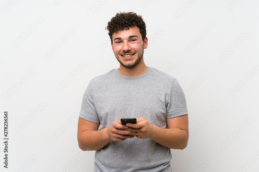 Man with curly hair over isolated wall using mobile phone Man with curly hair over isolated wall using mobile phone