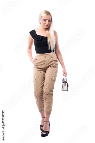 Happy stylish elegant style blonde woman with handbag walking and looking down. Full body isolated on white background.