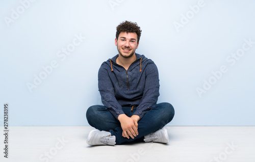 Young man sitting on the floor laughing © luismolinero