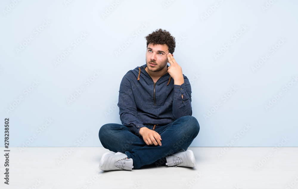 Young man sitting on the floor with problems making suicide gesture Young man sitting on the floor with problems making suicide gesture