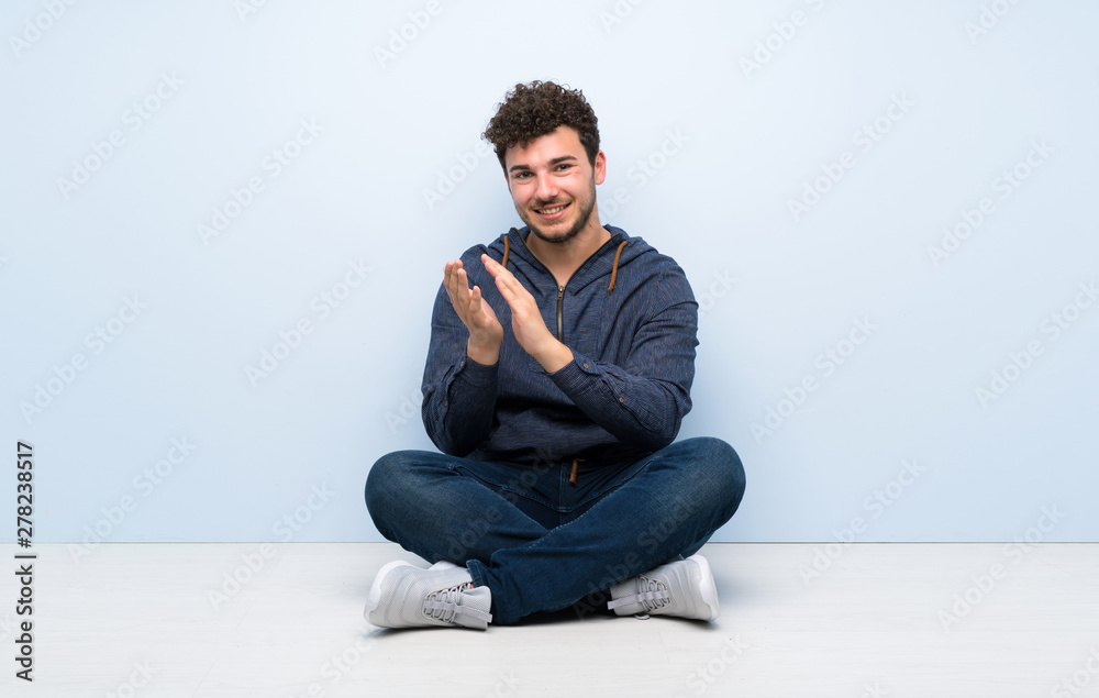 Young man sitting on the floor applauding after presentation in a conference Young man sitting on the floor applauding after presentation in a conference