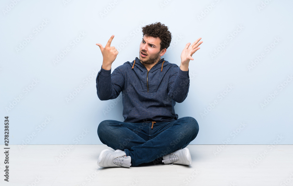 Young man sitting on the floor counting seven with fingers