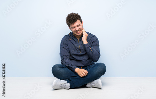 Young man sitting on the floor with toothache © luismolinero