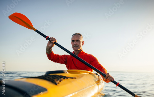 Active senior man paddling kayak photo