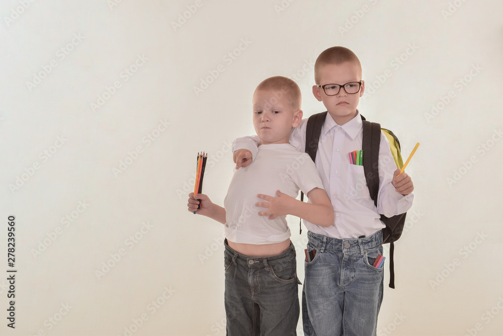two blond Cute boys with schoolbag shows his emotions and gesture. Little actor tries role. Children in white clother with pencils