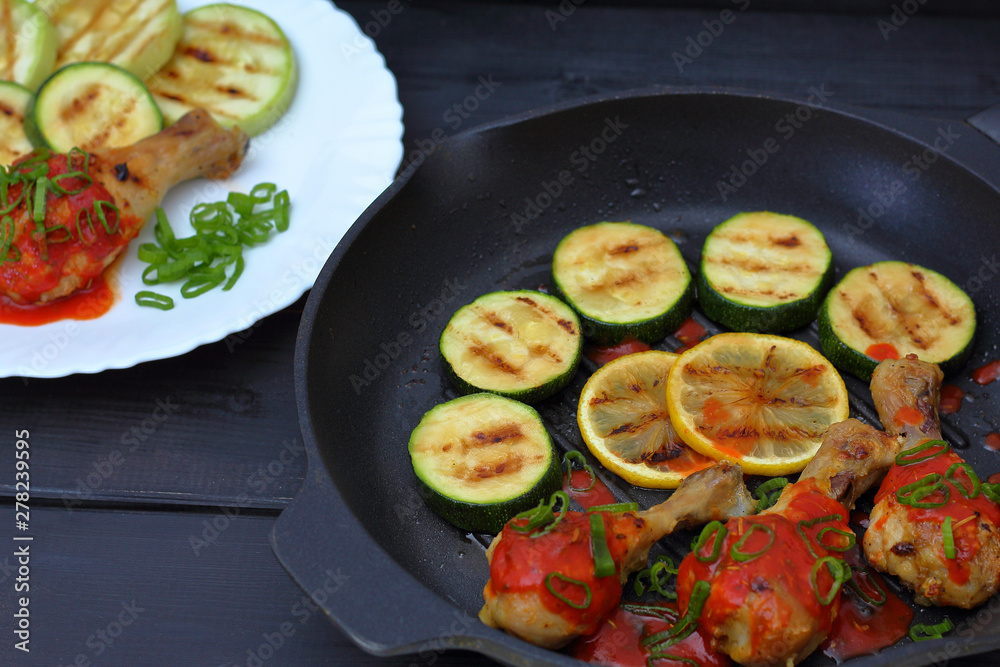 grilled chicken, tomato sauce and zucchini on a plate, black background grilled chicken, tomato sauce and zucchini on a plate, black background