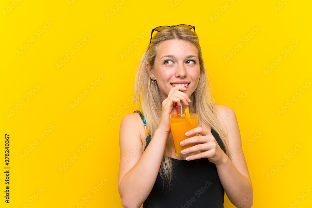 Young woman in swimsuit over yellow background with a cocktail Young woman in swimsuit over yellow background with a cocktail