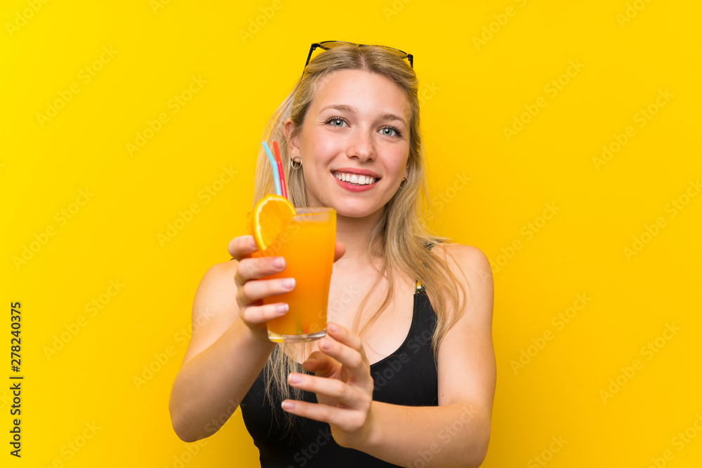 Young woman in swimsuit over yellow background with a cocktail Young woman in swimsuit over yellow background with a cocktail