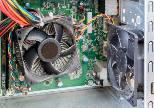 The interior casing of a PC computer showing very dusty cooling fans, sinks and circuit board