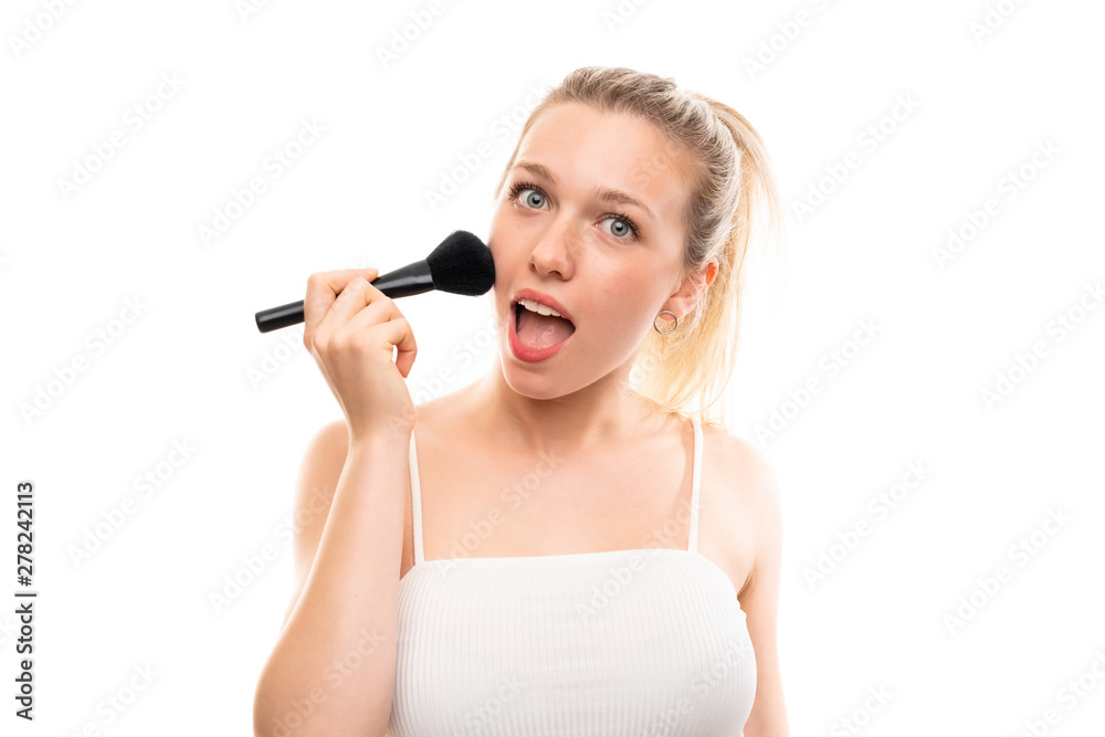 Young blonde woman over isolated white background with makeup brush Young blonde woman over isolated white background with makeup brush