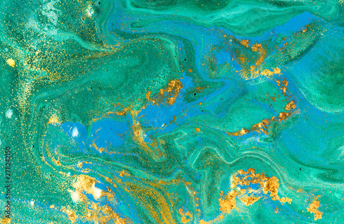 Liquid uneven blue and green marbling pattern with golden glitter and glare of light