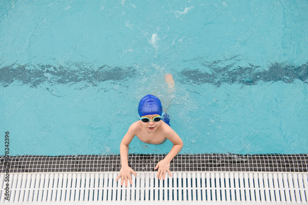 top view of a 7-year boy playing and swimming in the swimming pool