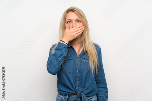 Young blonde woman over isolated white wall covering mouth with hands © luismolinero