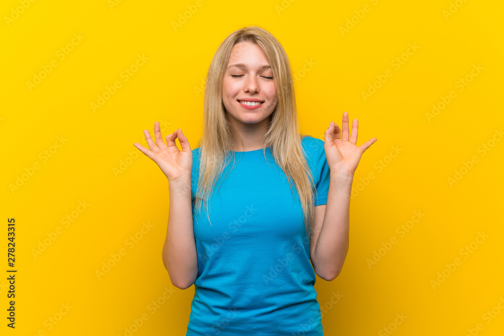 Young blonde woman over isolated yellow background in zen pose Young blonde woman over isolated yellow background in zen pose