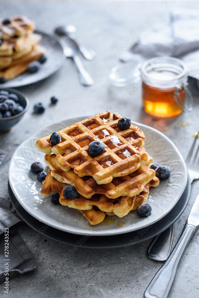 Viennese waffles with honey and blueberries on the background, selective focus Viennese waffles with honey and blueberries on the background, selective focus
