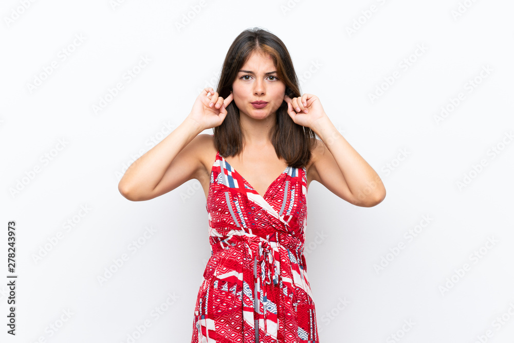 Caucasian girl in red dress over isolated white wall frustrated and covering ears Caucasian girl in red dress over isolated white wall frustrated and covering ears