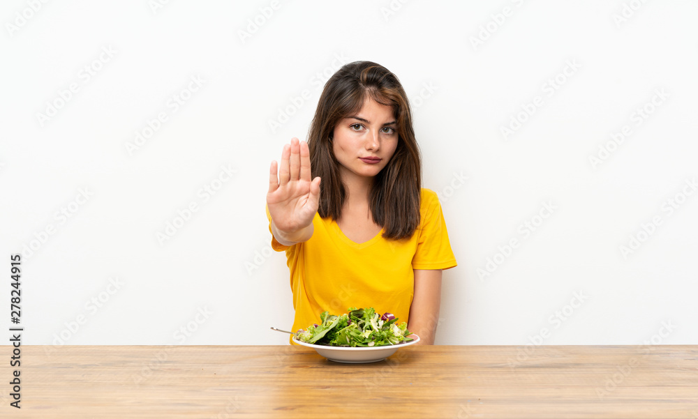 Caucasian girl with salad making stop gesture with her hand Caucasian girl with salad making stop gesture with her hand