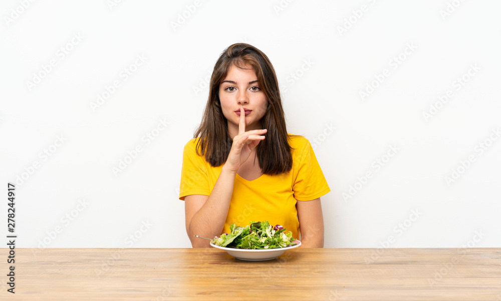 Caucasian girl with salad doing silence gesture