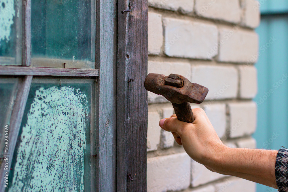 Hand hammers a nail into an old wooden frame Hand hammers a nail into an old wooden frame