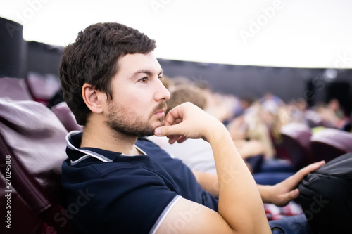 MOSCOW, RUSSIA - JULY 6: Exhibition in Moscow Planetarium. Young man sitting and watching education movie about solar sistem at the planetarium stadium