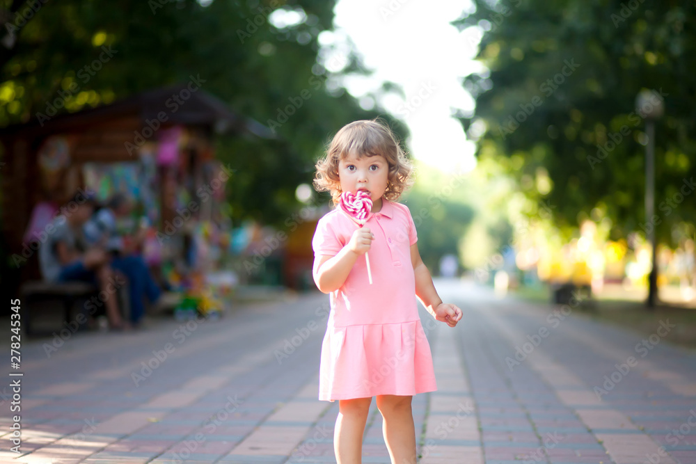 Beautiful little girl holding a big heart shaped lollipop Beautiful little girl holding a big heart shaped lollipop