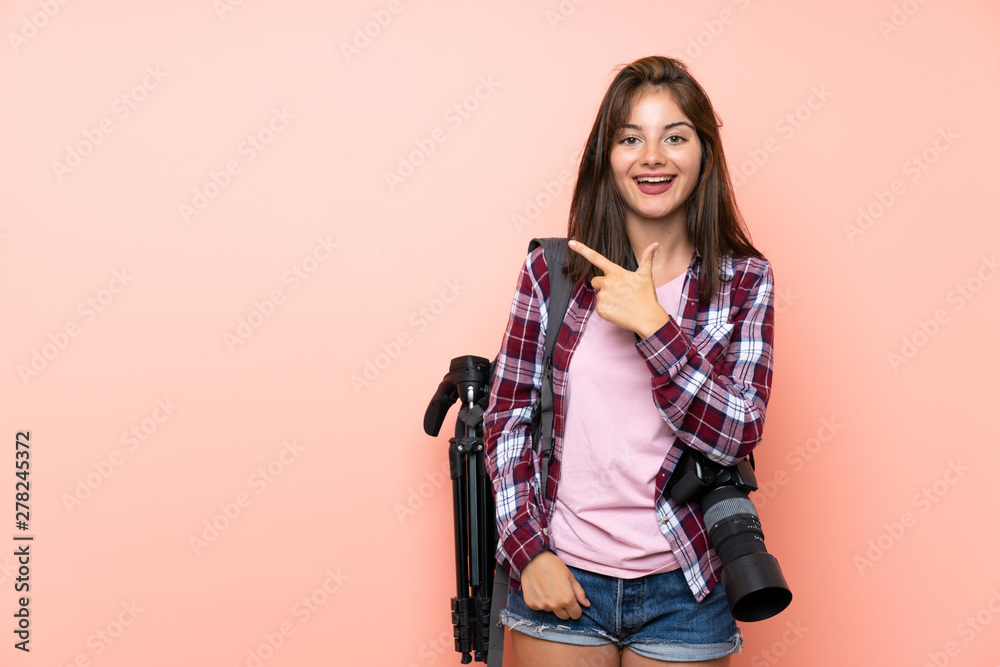 Young photographer girl over isolated pink background pointing finger to the side Young photographer girl over isolated pink background pointing finger to the side