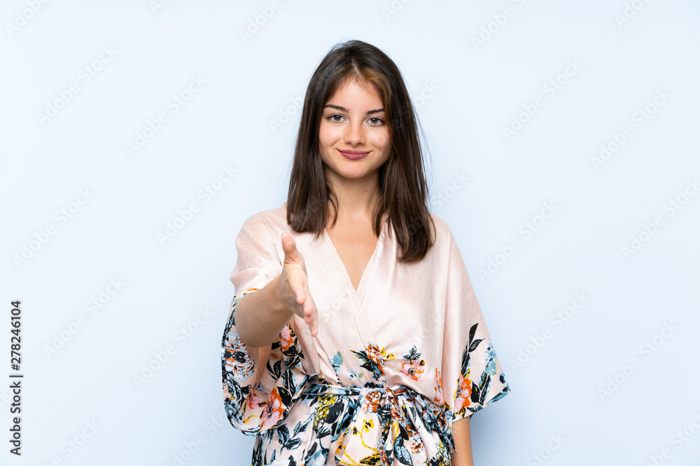 Caucasian girl with kimono over isolated blue background handshaking after good deal Caucasian girl with kimono over isolated blue background handshaking after good deal